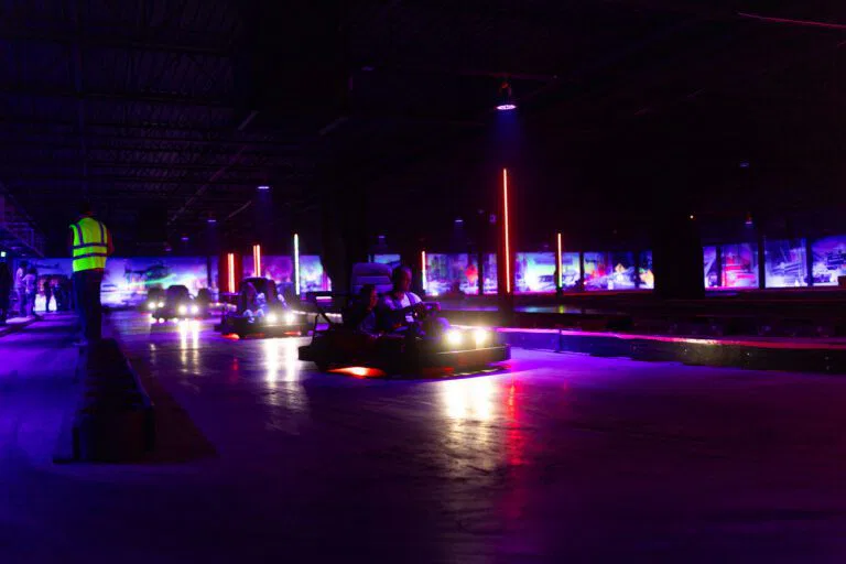 Two individuals in go-karts racing under the night sky at The Rush Funplex, enhanced by vibrant lighting and energy.